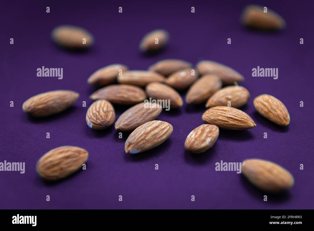 A closeup of delicious crunchy almonds with a purple background. Stock Photo