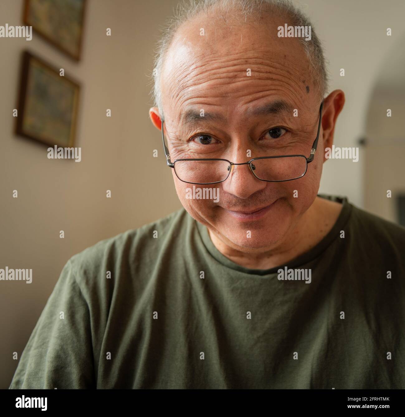 A kind, happy elderly Asian man at home with a smiling facial expression. Stock Photo