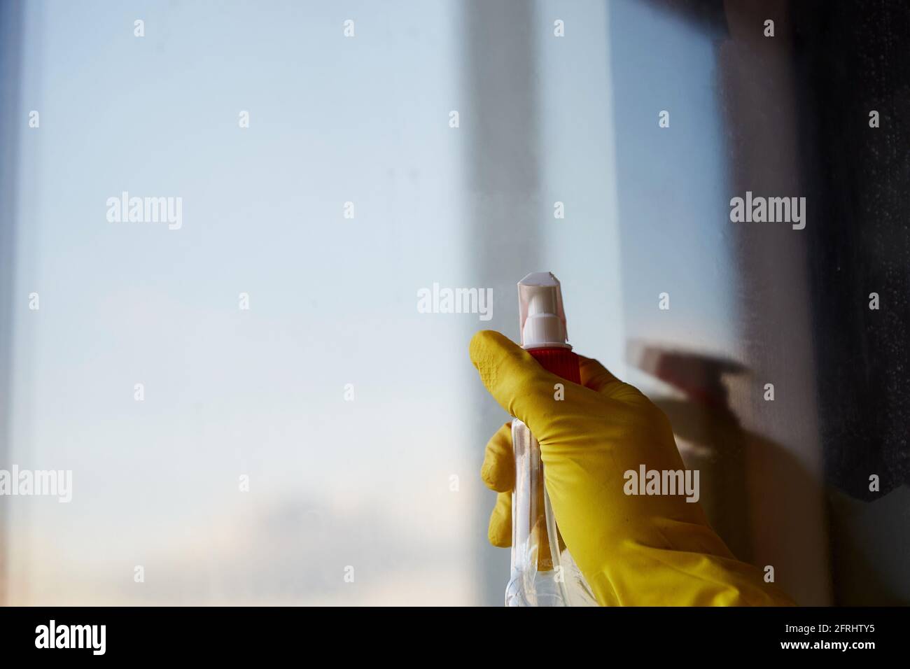 Spring cleaning concept. Sanitize and cleanliness through the pandemic, covid 19. Hand is washing window at home at evening light. Reflection effect. Copy space Stock Photo
