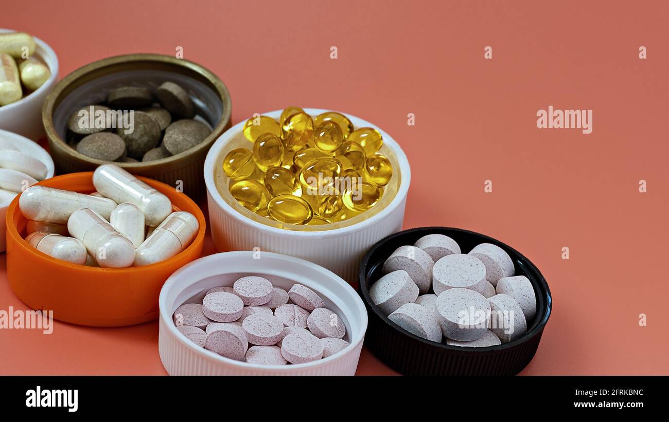 close-up of multivitamin biologically active supplements on coral background. mental wellbeing and  personal health concept Stock Photo