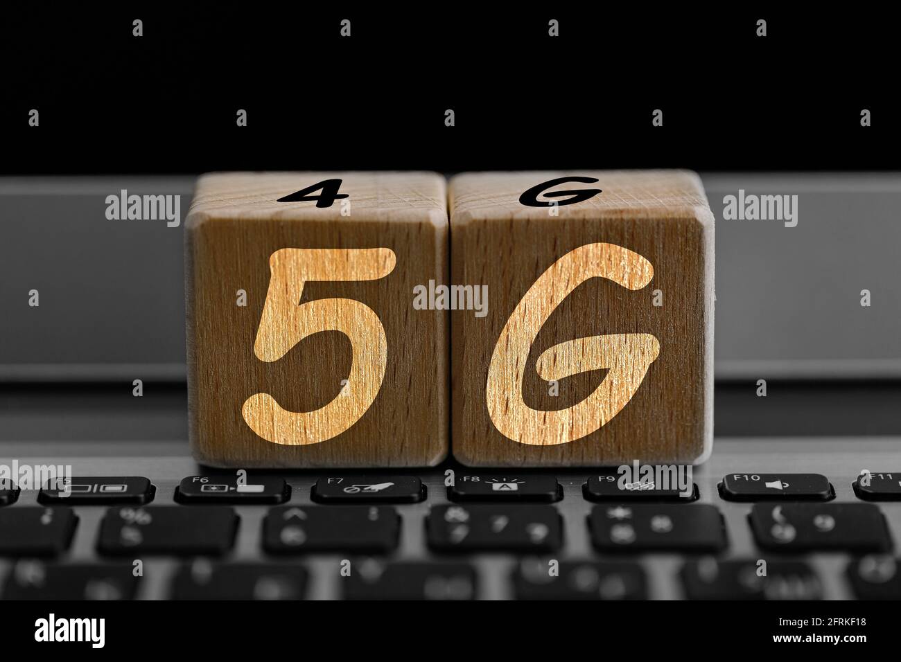photo on 5G network theme. wooden cubes with the acronym "5G", on the background of laptop Stock Photo