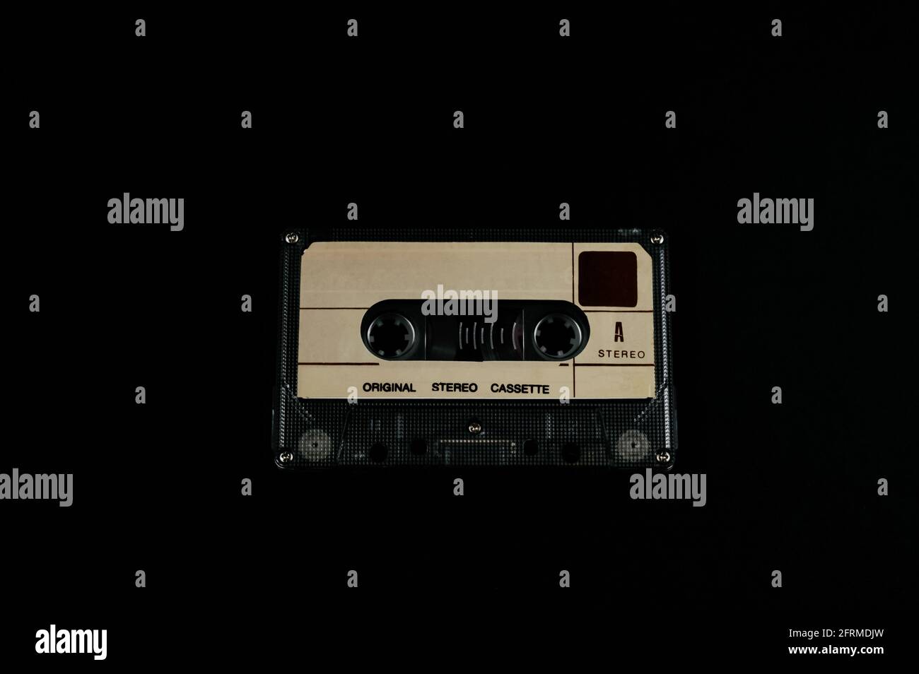 Audio cassette on a black background. Compact tape cassette an analog magnetic tape recording format for audio recording and playback. Stock Photo