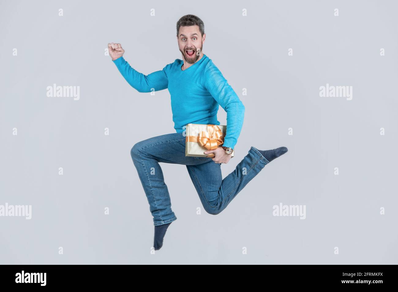 jumping handsome man with present box. businessman giving birthday gift. energetic unshaven man Stock Photo