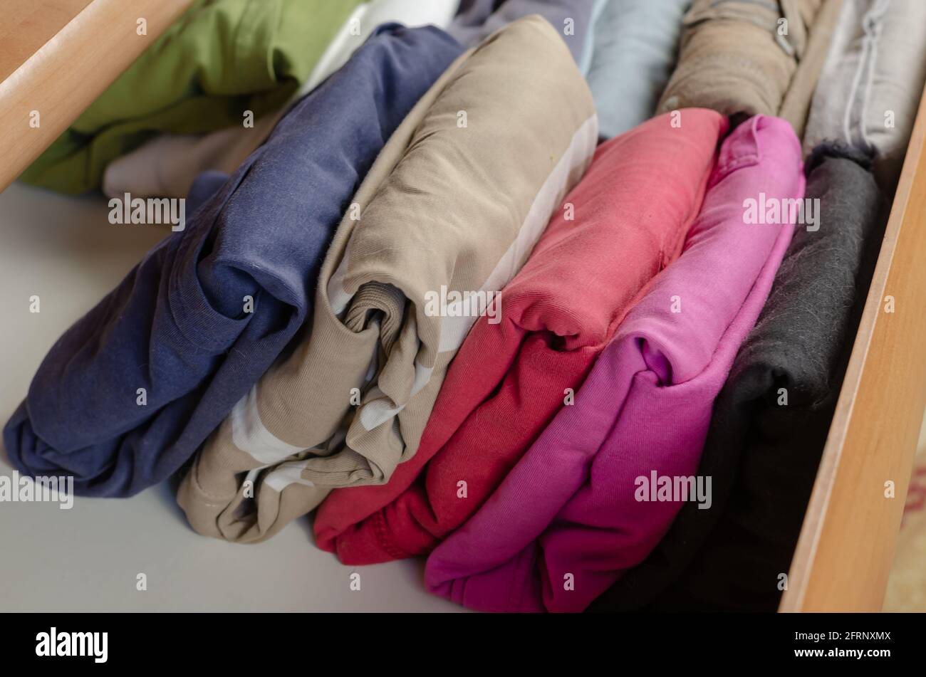 Concept Vertical Japanese clothes storage system. Multicolored shirts