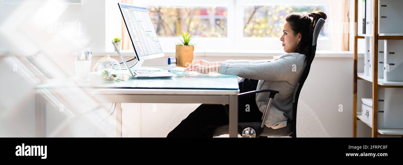 Bad Posture Sitting In Office Chair At Computer Desk Stock Photo