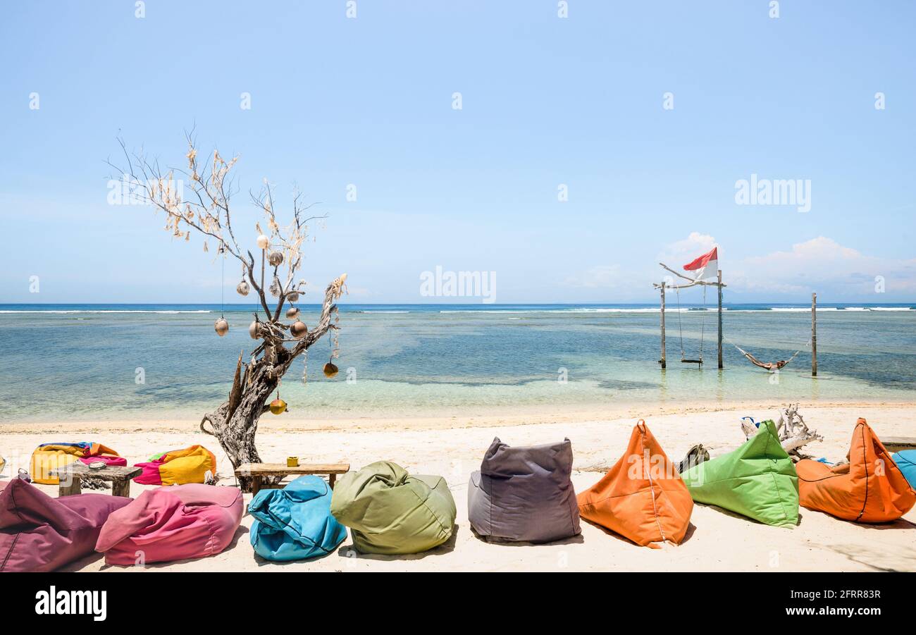 Gili Trawangan beach on a sunny day with multicolored sofas at chilling lounge - Travel and vacation concept with beautiful destinations worldwide Stock Photo