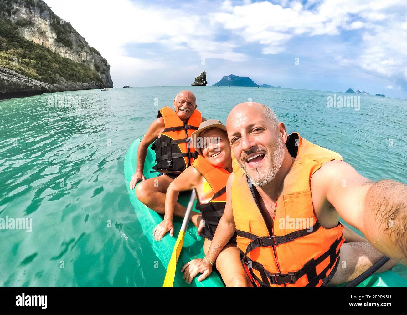 Senior mother and father with son taking selfie at kayak excursion in Thailand - Adventure travel in south east asia - Elderly and family concept Stock Photo