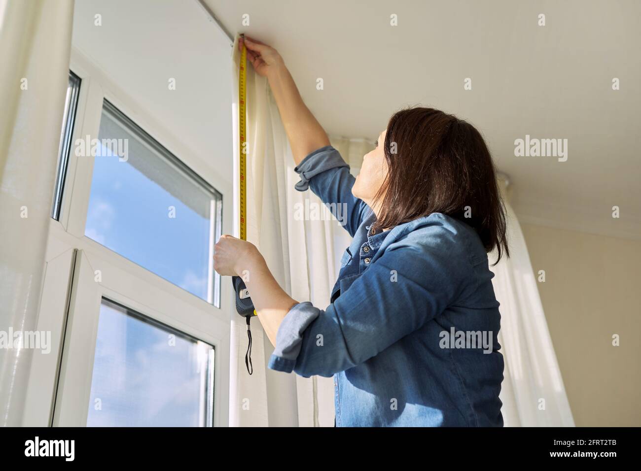 Service for sewing and hanging curtains. Woman with tape measure