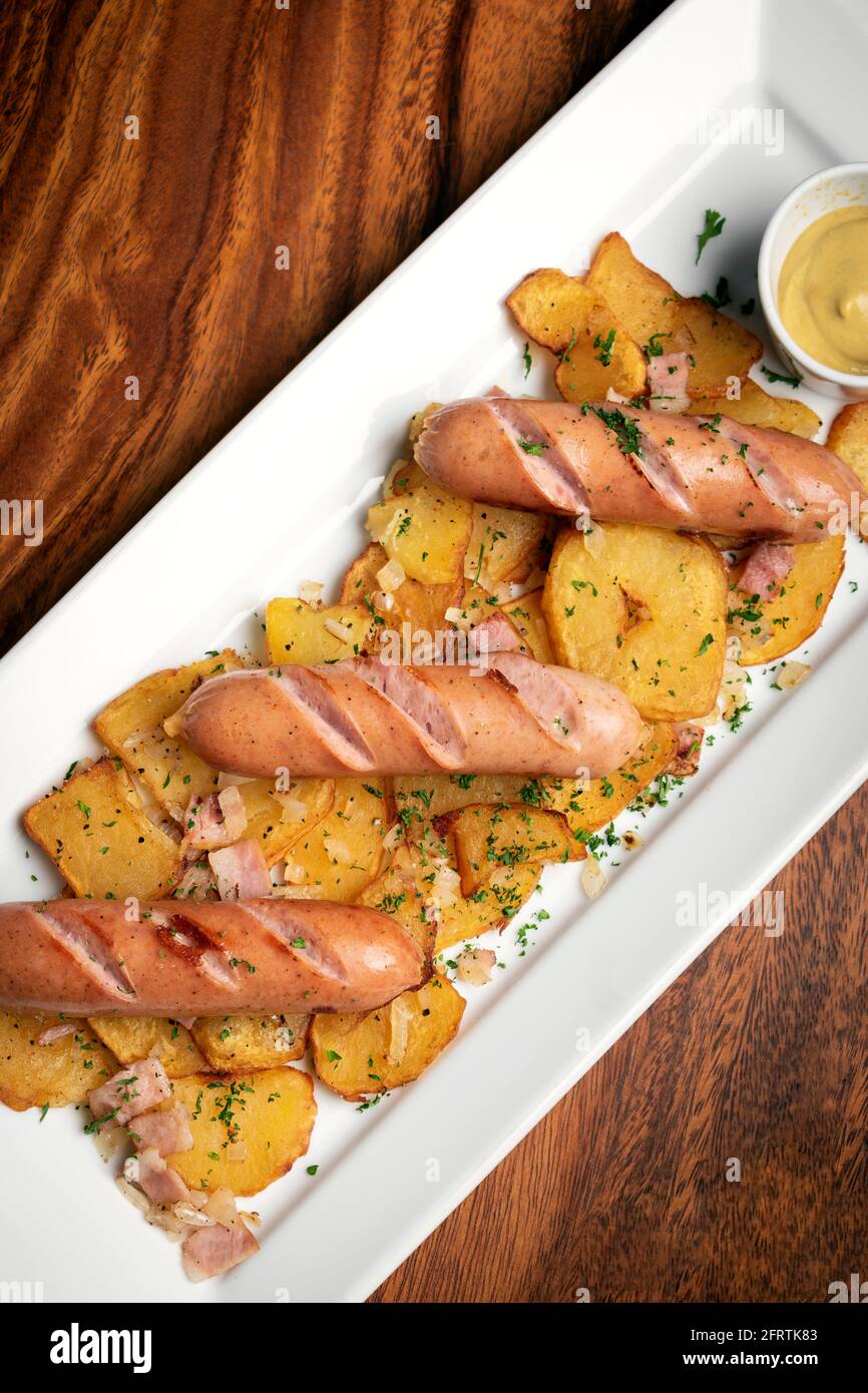 german organic cheese and pork sausages with fried potato and mustard on wood background Stock Photo