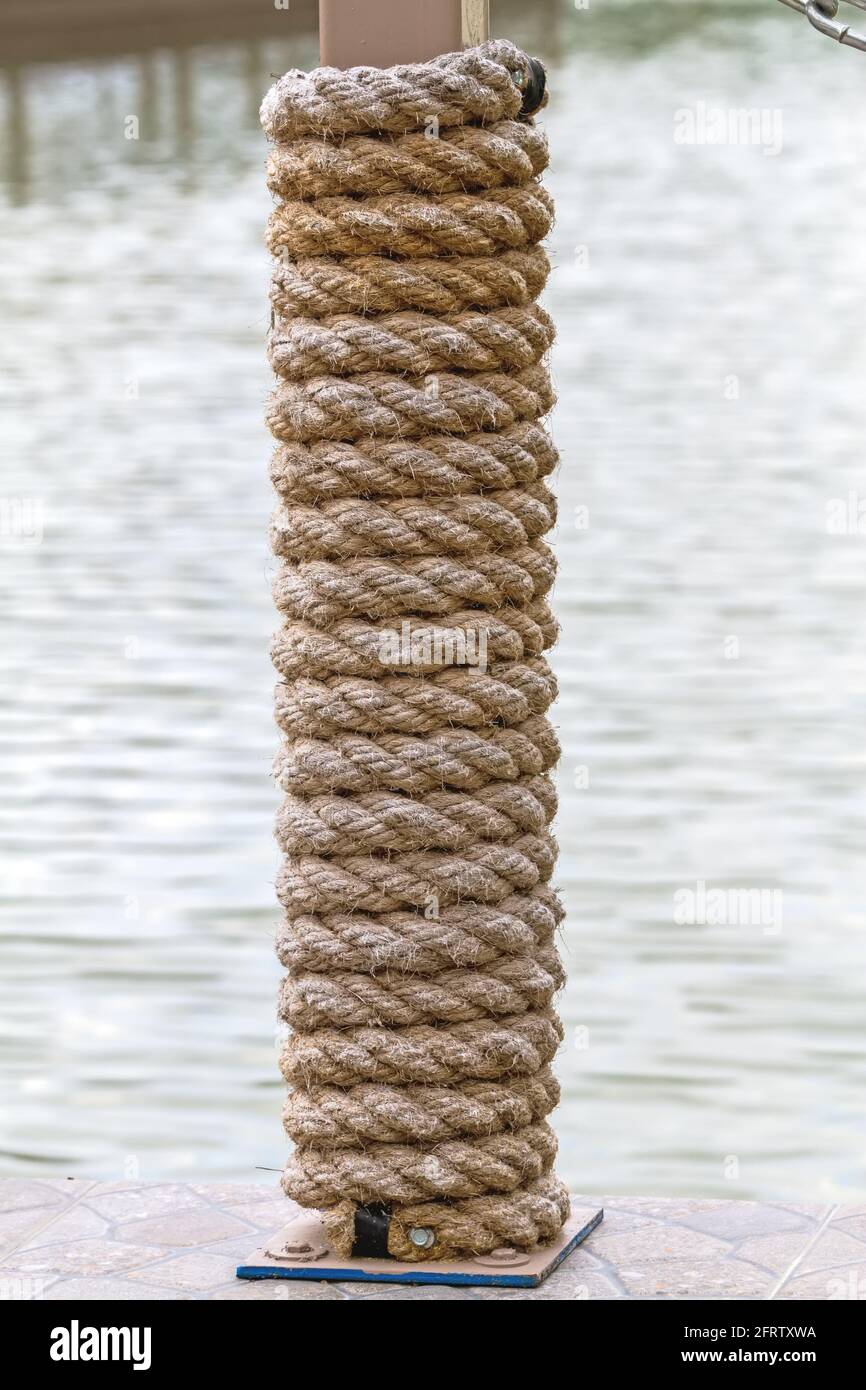 Many layers of rope tied around a wooden log, in the shade on a sunny ...