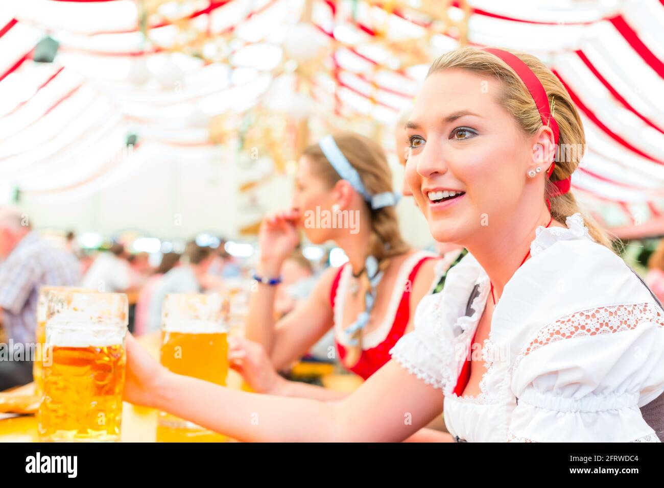 Women drinking Bavarian beer in tent on Oktoberfest or dult wearing dirndl Stock Photo