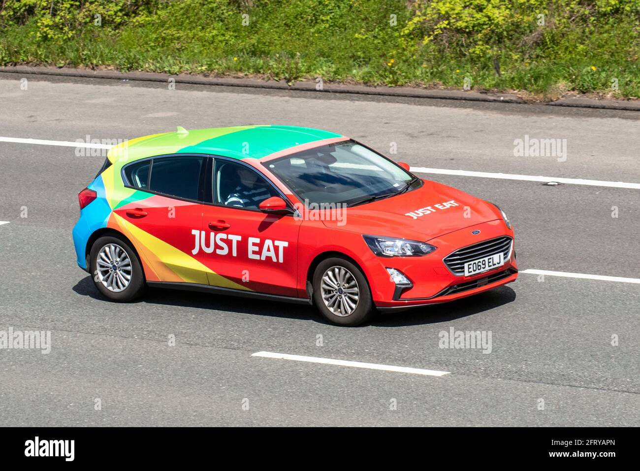 Just Eat 2019 Ford Focus Titanium Tdci red diesel hatchback; Vehicular traffic moving vehicles, catering commercial vans, foods courier on the Just Eat network, takeaway food business vehicles, livered cars driving vehicle on UK roads, motors, motoring on the M6 motorway highway network. Stock Photo