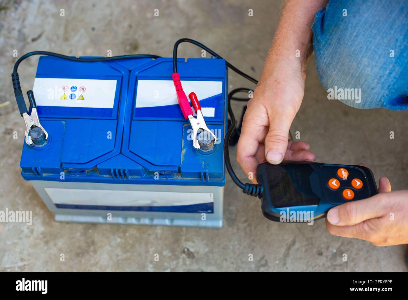 Testing the charging of VARTA car batteries with an electronic multimeter. Stock Photo