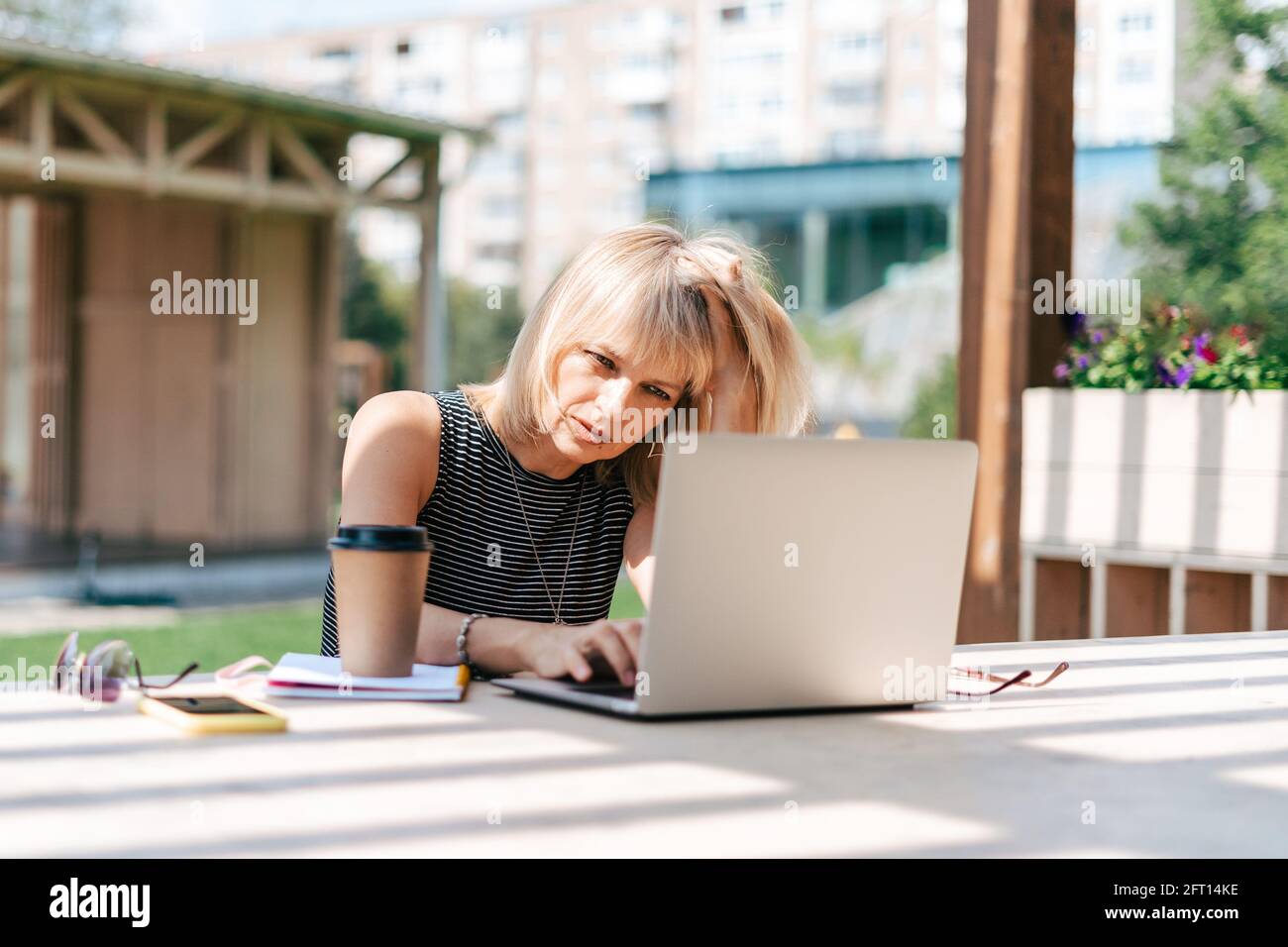 Serious thinking woman working at laptop outside Stock Photo