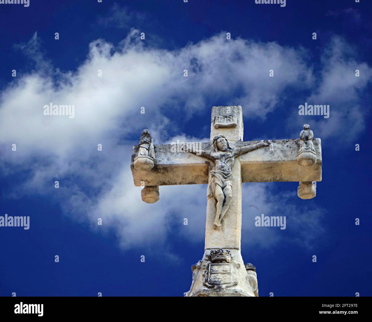 Jesus at the Cross, stone cross in front of blue sky with white clouds, 2021 Stock Photo