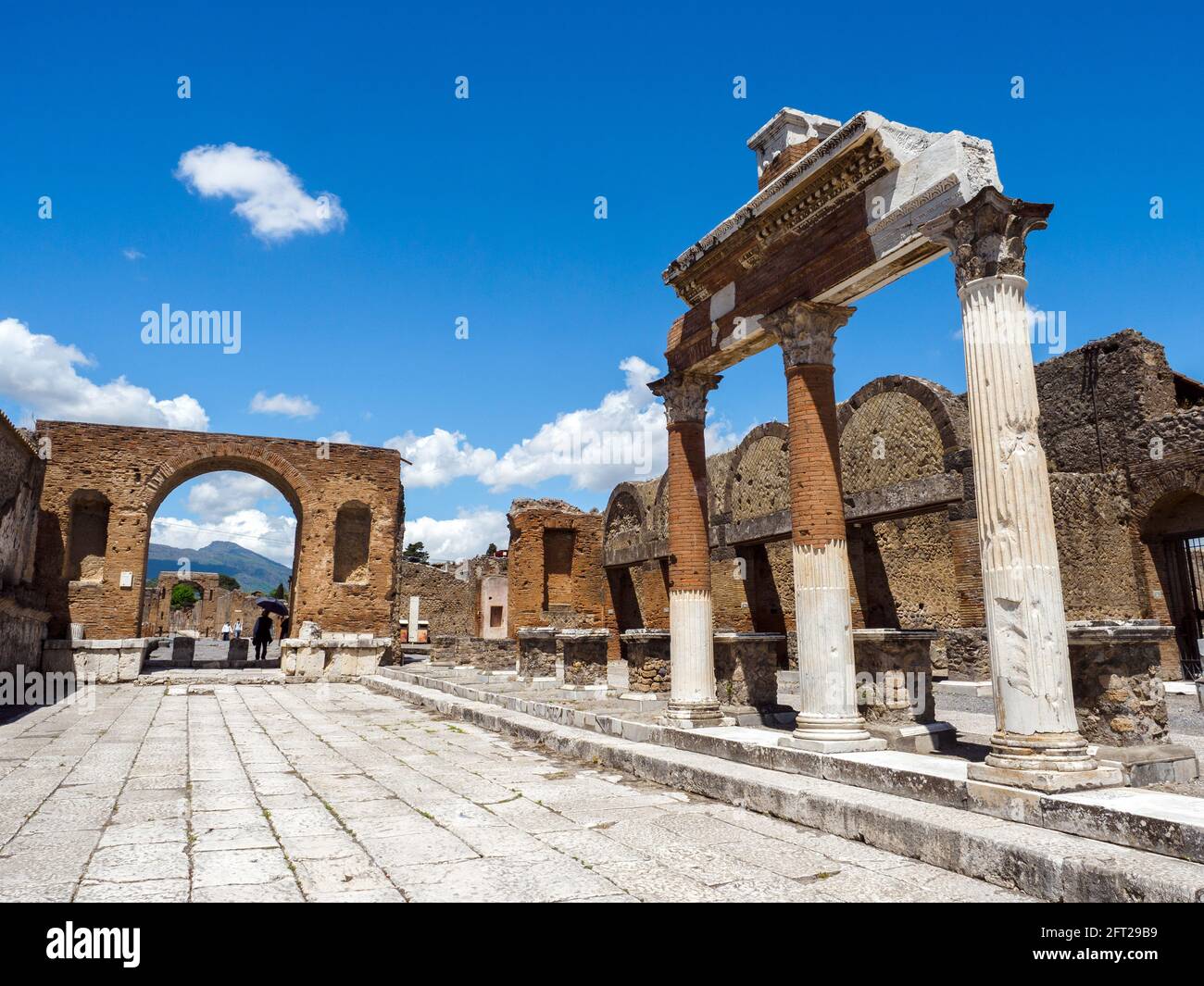 Honorary arch of Tiberius and fragments of the Corinthian columns belonging to the Macellum or food market in the forum - Pompeii archaeological site, Italy Stock Photo