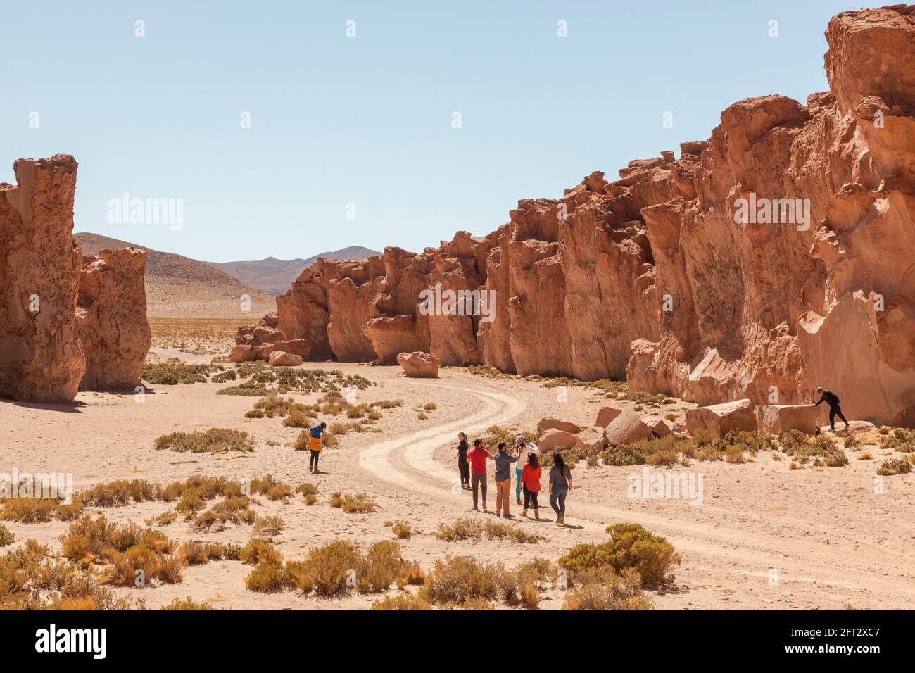 A group of tourists walk through a rocky canyon in Bolivia's Atacama desert. Stock Photo