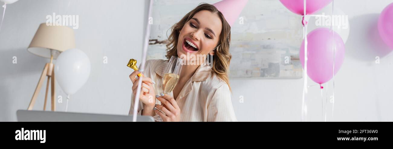 Positive Woman With Party Blower And Champagne Having Video Chat On Laptop At Home Banner Stock Photo Alamy