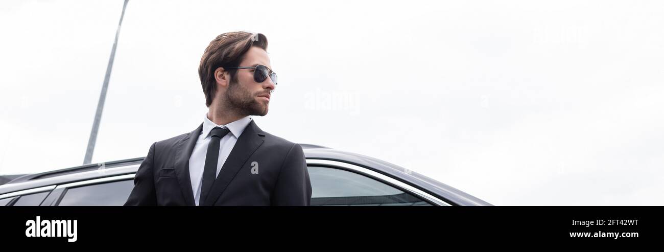 low angle view of bearded bodyguard in sunglasses and suit standing ...