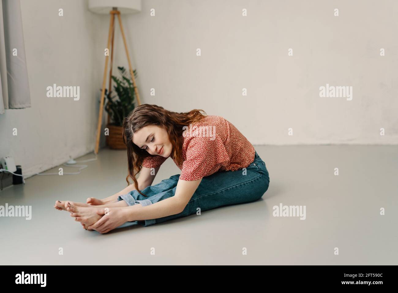 Supple flexible young woman doing toe stretches on the floor as she performs her daily workout to tone and strengthen her muscles in a health and fitn Stock Photo