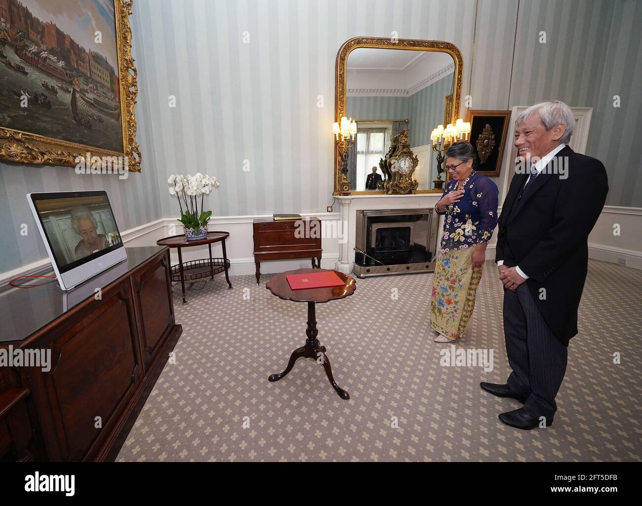 Queen Elizabeth II appears on a screen by videolink from Windsor Castle, where she is in residence, during a virtual audience to receive His Excellency Lim Tuan Kuan, the High Commissioner for the Republic of Singapore, and his wife Patricia Teh, at Buckingham Palace, London. Picture date: Friday May 21, 2021. Stock Photo