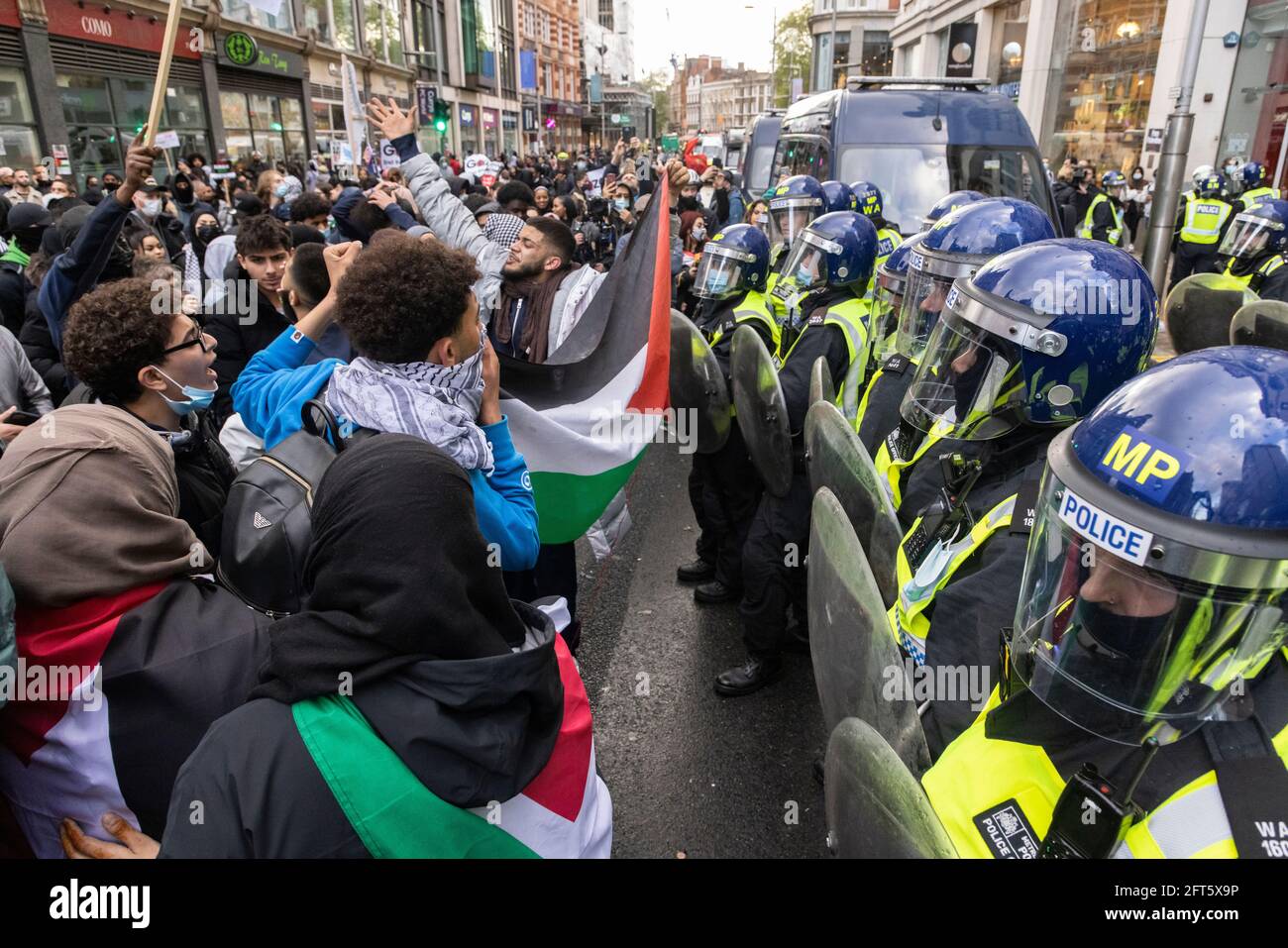 Protesters hold a Palestinian flag in front of police, 'Free Palestine' protest, London, 15 May 2021 Stock Photo
