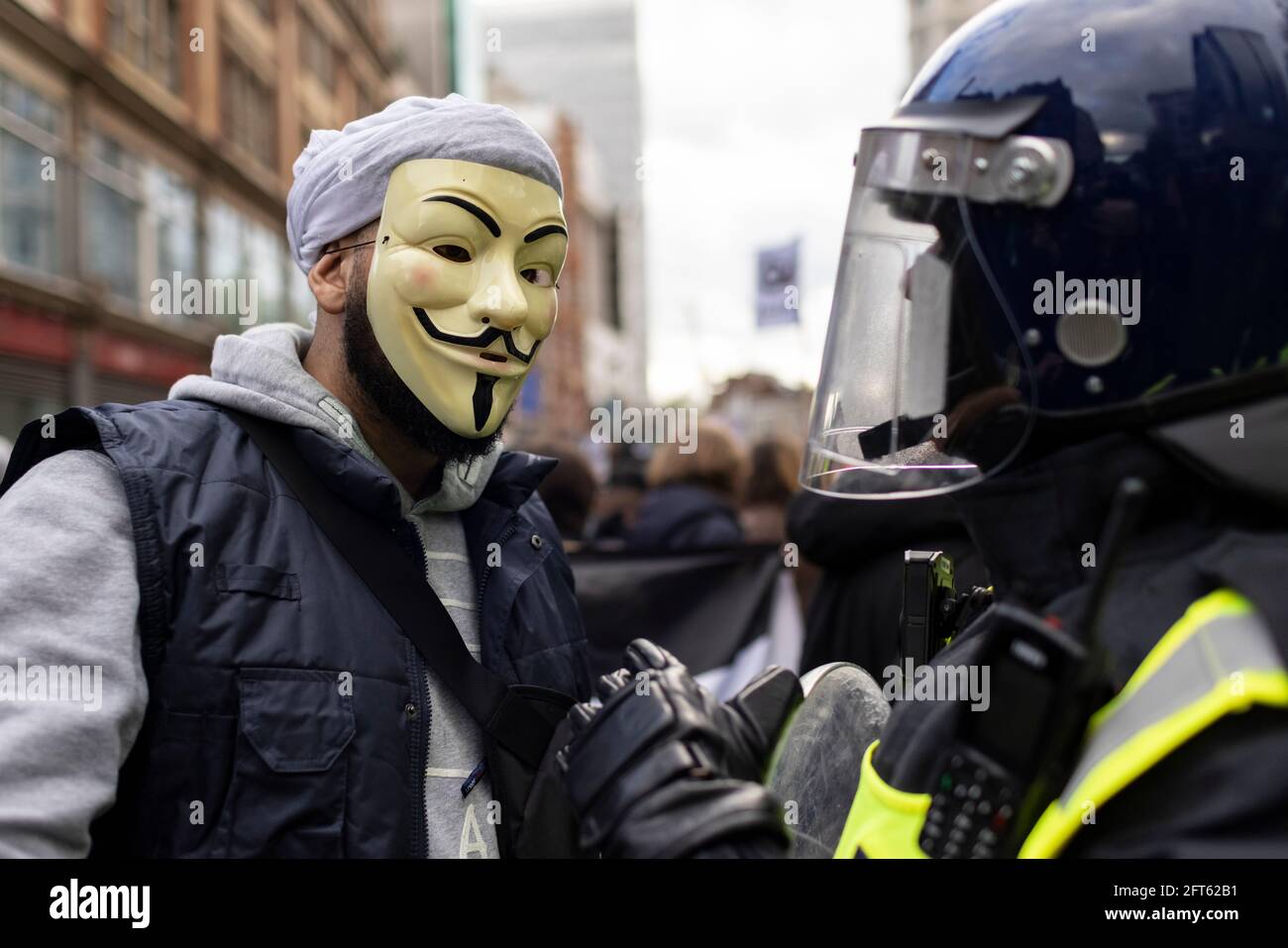 Protester in Guy Fawkes mask talks with riot police officer, 'Free