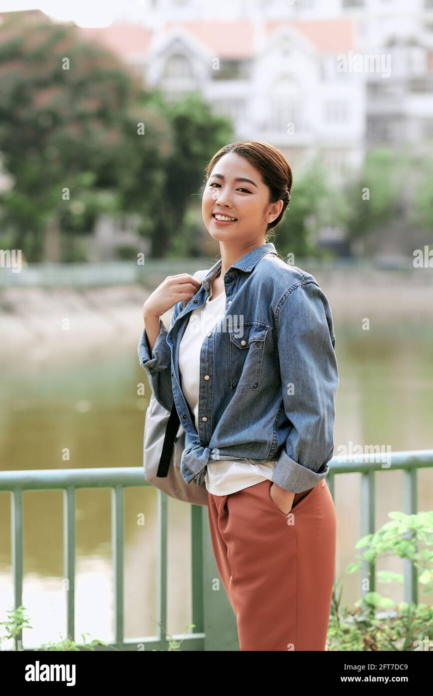 Portrait of young stylish woman walking on the street, wearing cute trendy outfit, smiling enjoy her weekends, travel with backpack Stock Photo