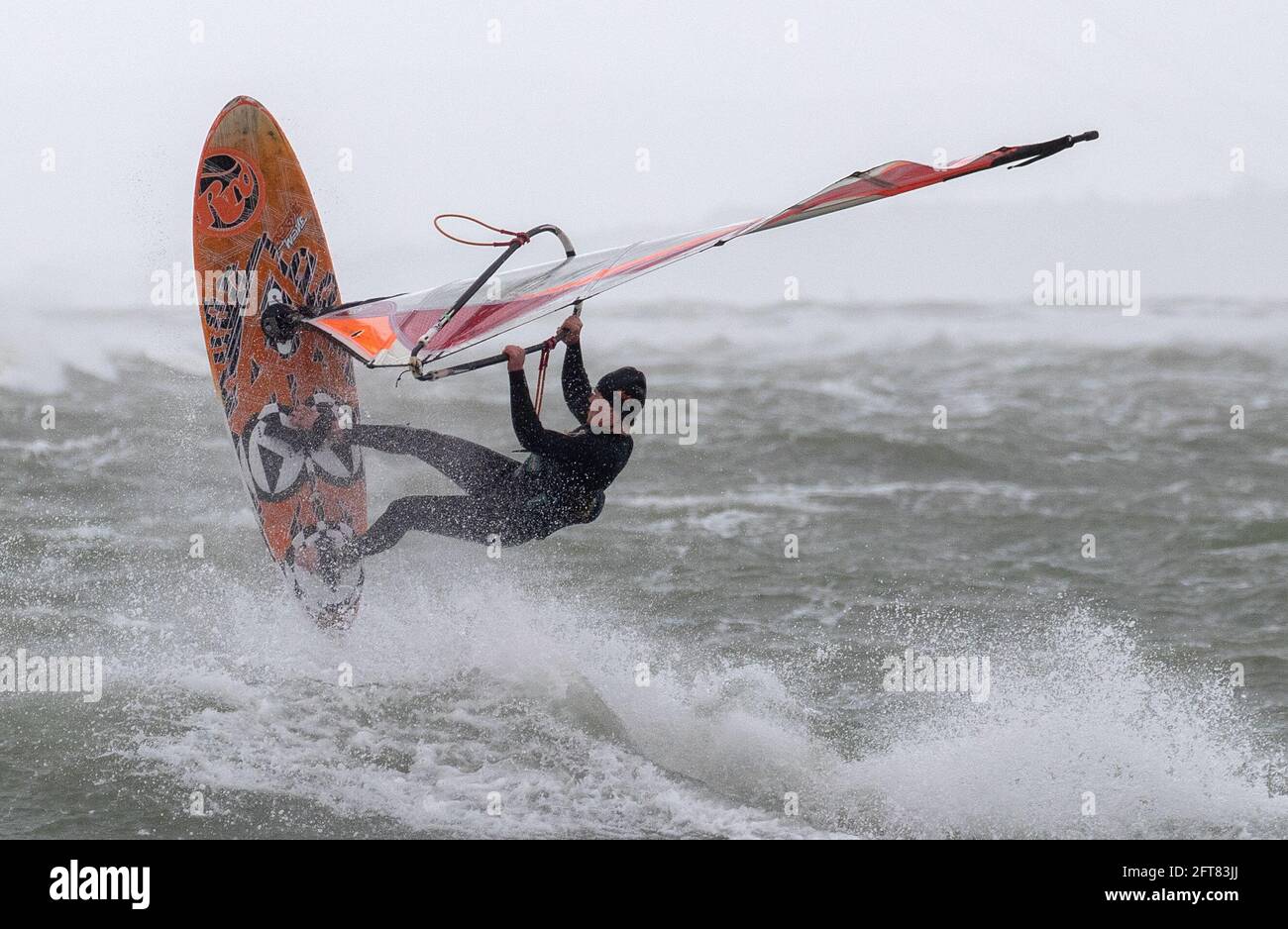 A windsurfer jumps in the air after hitting a wave in the rough sea off