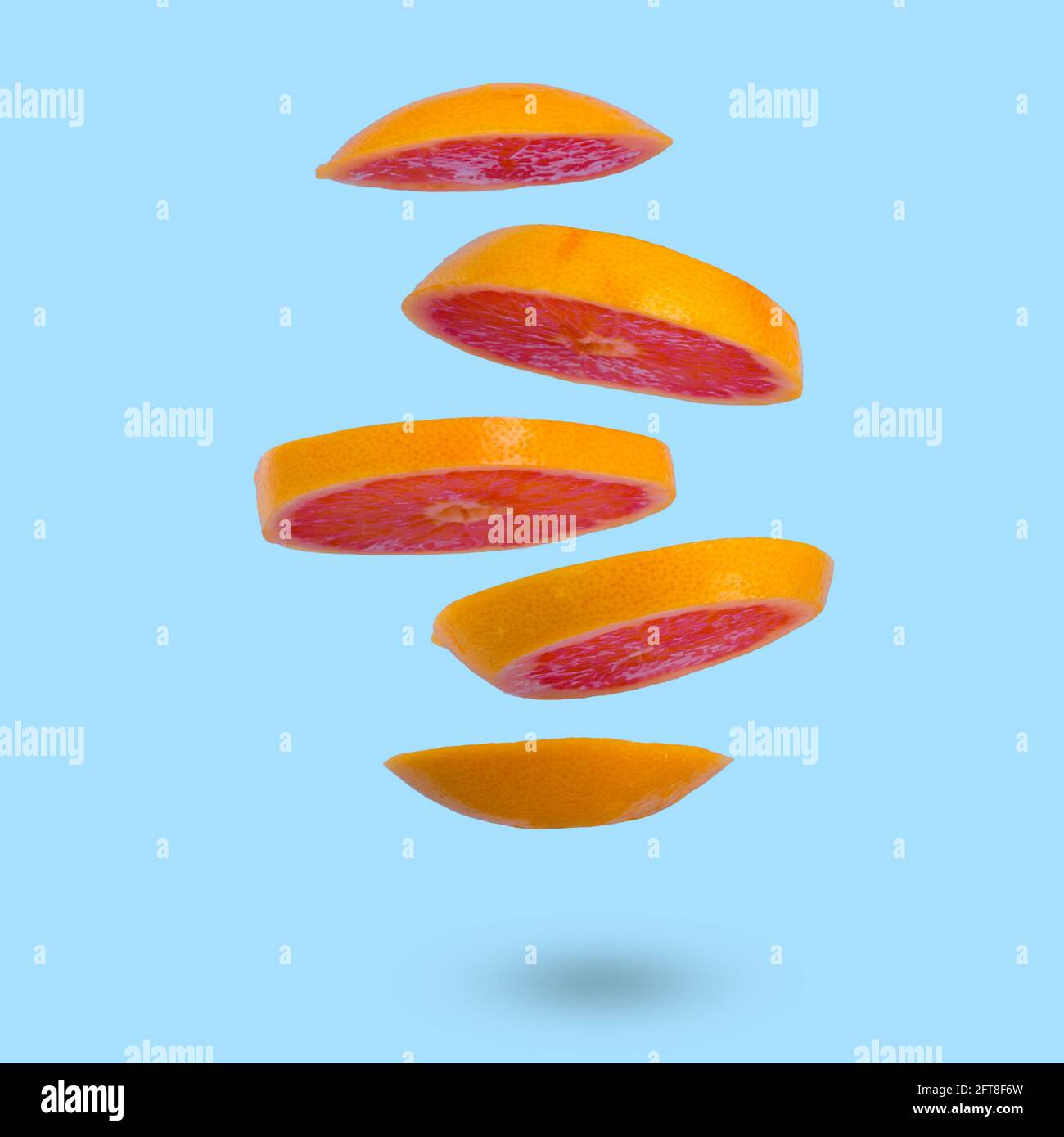 Floating levitating ripe grapefruit on a light blue background. Vitamins, healthy diet concept. Minimal fruit idea. Sliced grapefruit floating in the Stock Photo