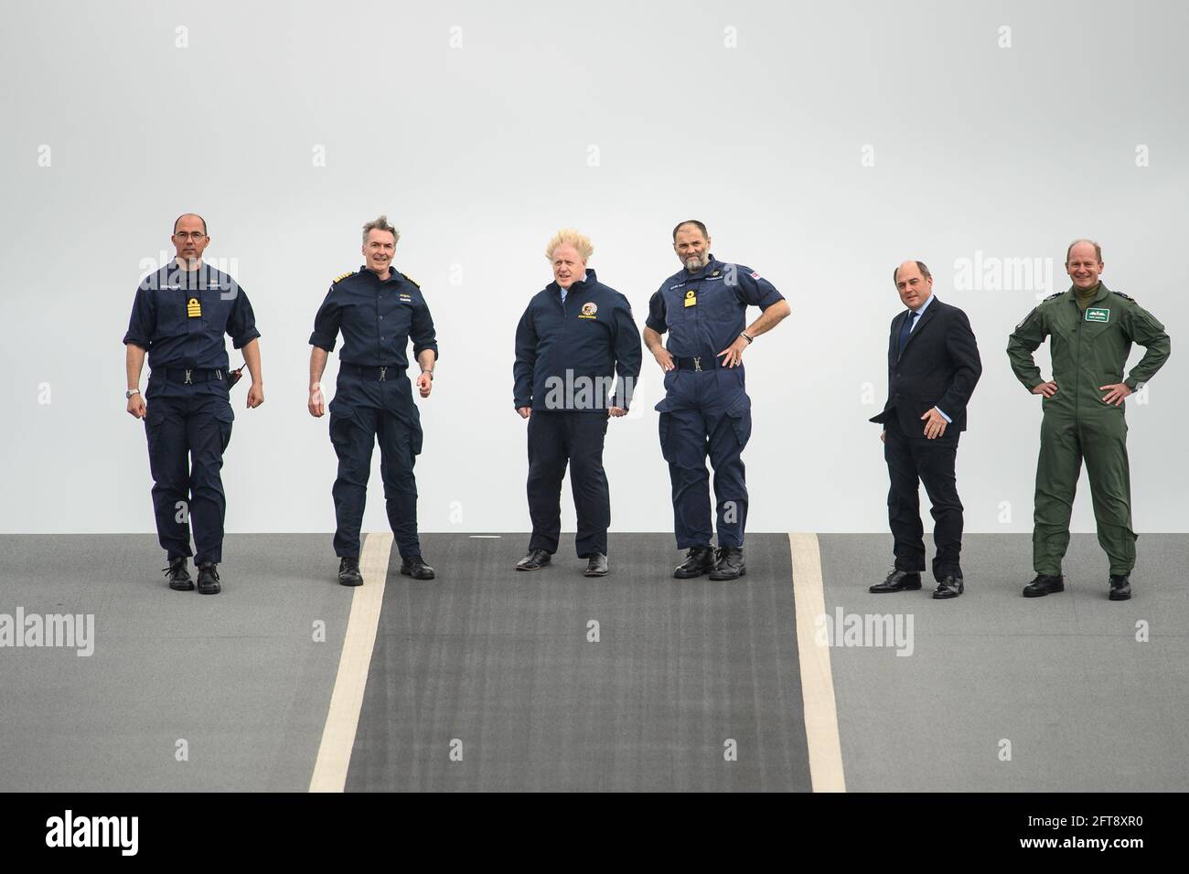 (Left to right) Captain Angus Essenhigh, First Sea Lord Admiral Tony Radakin, Prime Minister Boris Johnson, Commodore Steve Moorhouse, Defence Secretary Ben Wallace and and Air Chief Marshal Sir Mike Wigston face strong winds as they walk on the flight deck, during a visit aboard HMS Queen Elizabeth in Portsmouth ahead of its first operational deployment to the Far East. Picture date: Friday May 21, 2021. Stock Photo
