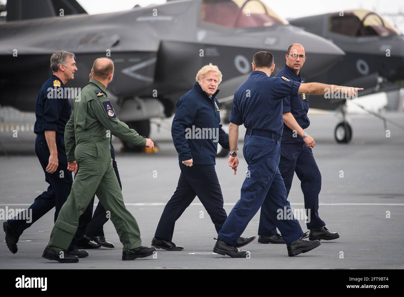 (Left to right) First Sea Lord Admiral Tony Radakin, Air Chief Marshal Sir Mike Wigston, Prime Minister Boris Johnson, Commodore Steve Moorhouse and Captain Angus Essenhigh face strong winds as they walk on the flight deck, during a visit aboard HMS Queen Elizabeth in Portsmouth ahead of its first operational deployment to the Far East. Picture date: Friday May 21, 2021. Stock Photo