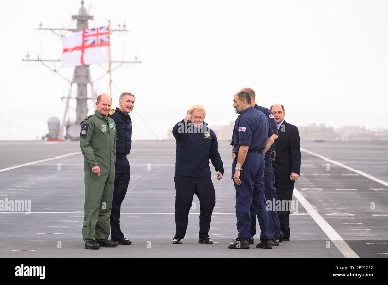 (Left to right) Air Chief Marshal Sir Mike Wigston, First Sea Lord Admiral Tony Radakin, Prime Minister Boris Johnson, Commodore Steve Moorhouse, Captain Angus Essenhigh and Defence Secretary Ben Wallace face strong winds as they walk on the flight deck, during a visit aboard HMS Queen Elizabeth in Portsmouth ahead of its first operational deployment to the Far East. Picture date: Friday May 21, 2021. Stock Photo