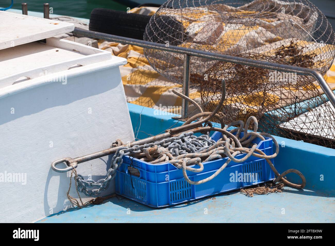 Small fishing boat equipment. Ropes, cages and anchor lay on a blue