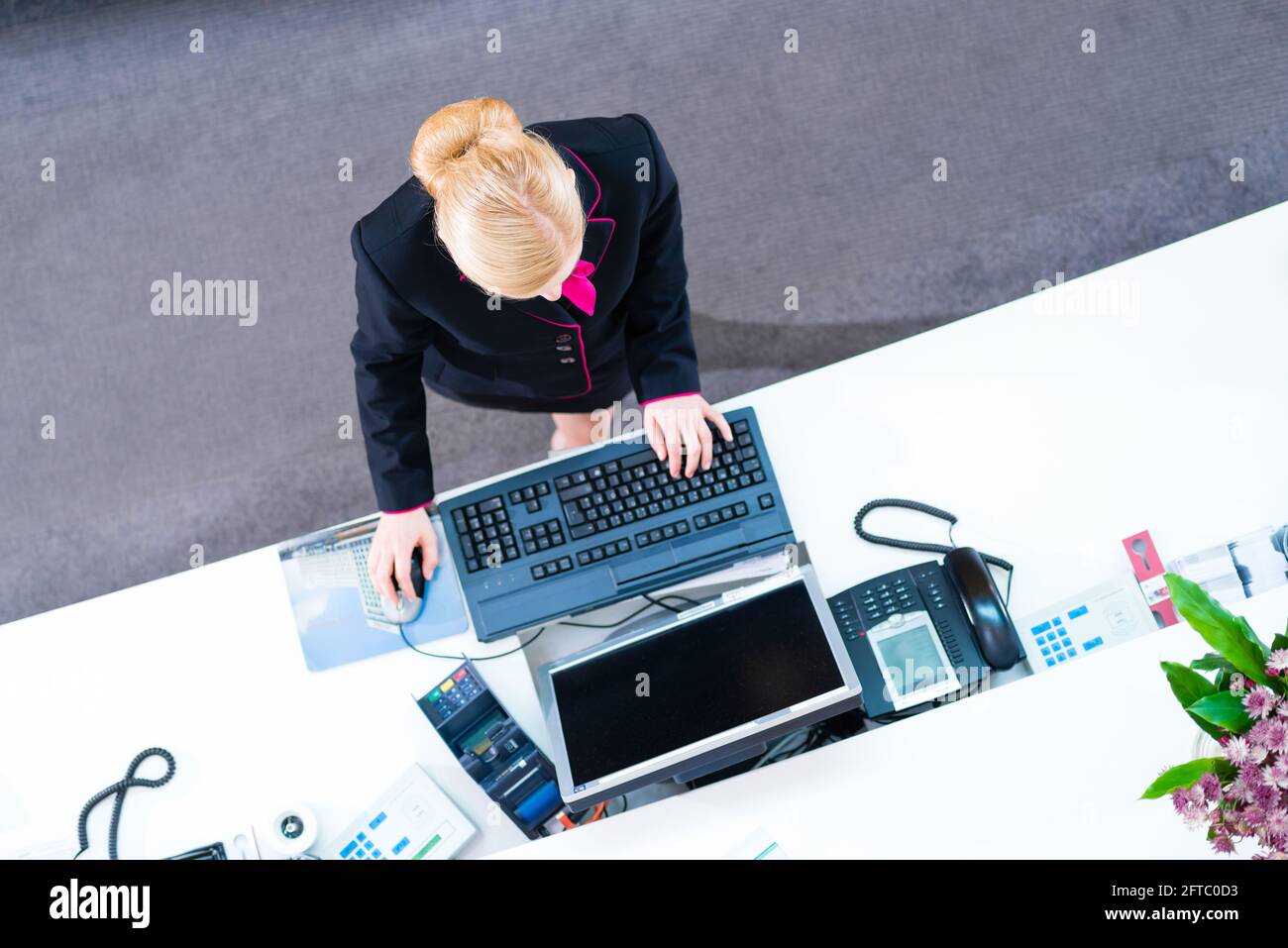 Hotel receptionist working on computer at front desk office Stock Photo ...