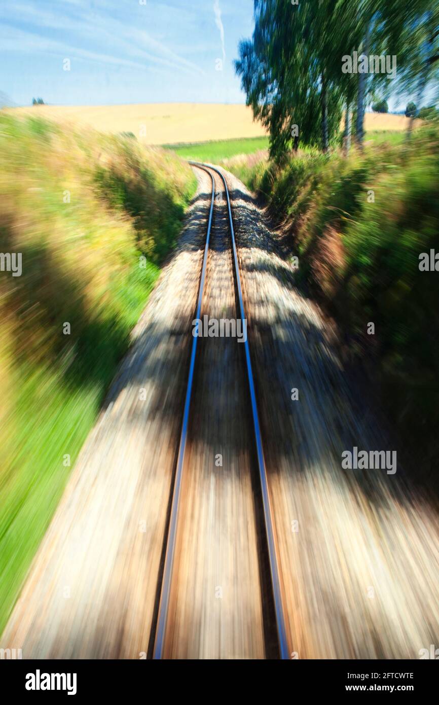 View of narrow gauge railroad track from rear window of train. Stock Photo