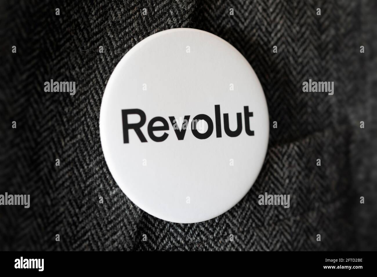 A button badge bearing the logo of Revolut Bank fastened to a suit jacket. Stock Photo