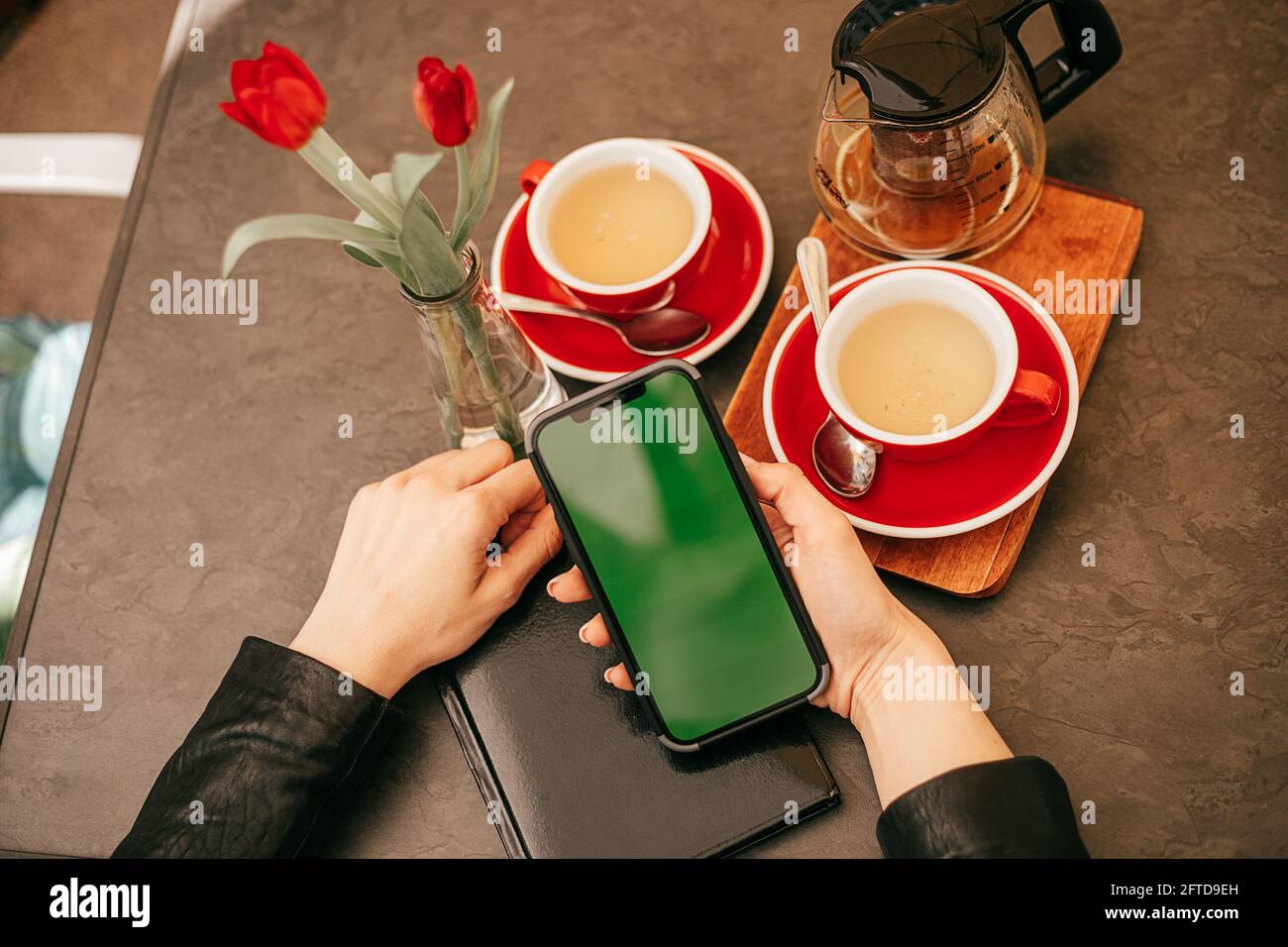 Chroma key phone screen in hands of woman drinking tea in cafe with ...