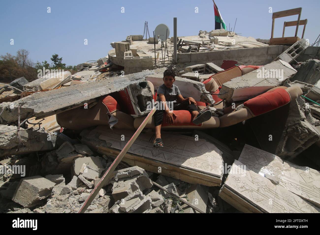 Gaza. 21st May, 2021. A Palestinian boy sits over the rubble of his ...