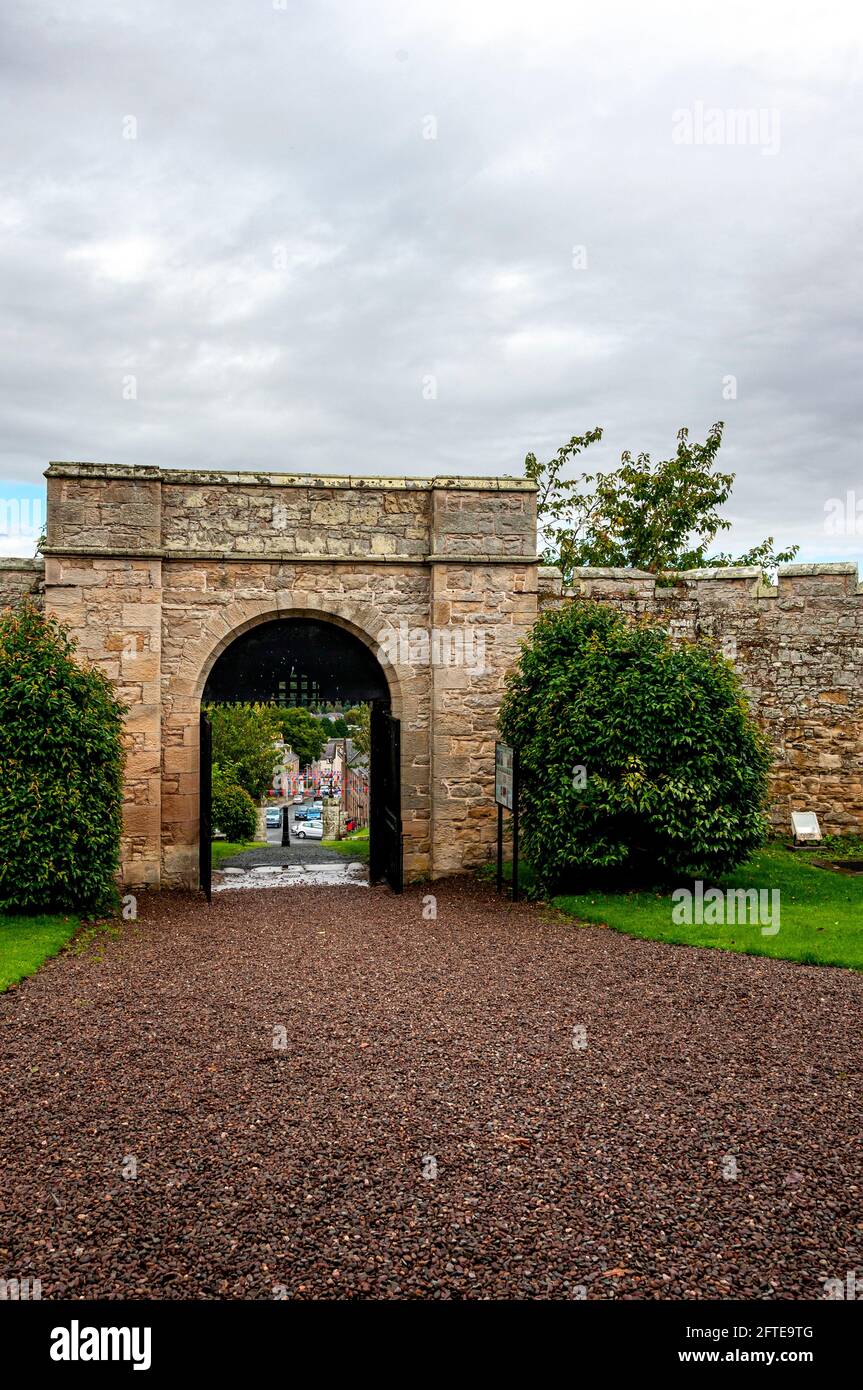 Castlegate seen through the flat topped, arched, main entrance gate to Jedburgh Jail with its sham portcullis and yett set in battlemented walls Stock Photo