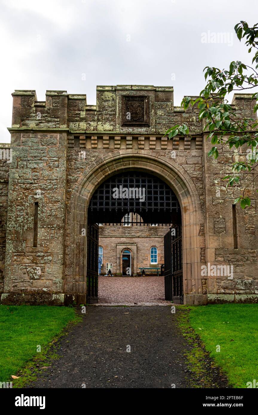 The Gaoler’s House seen through the arched, main entrance gate to Jedburgh Jail, flanked by small twin towers with its sham portcullis and yett open Stock Photo