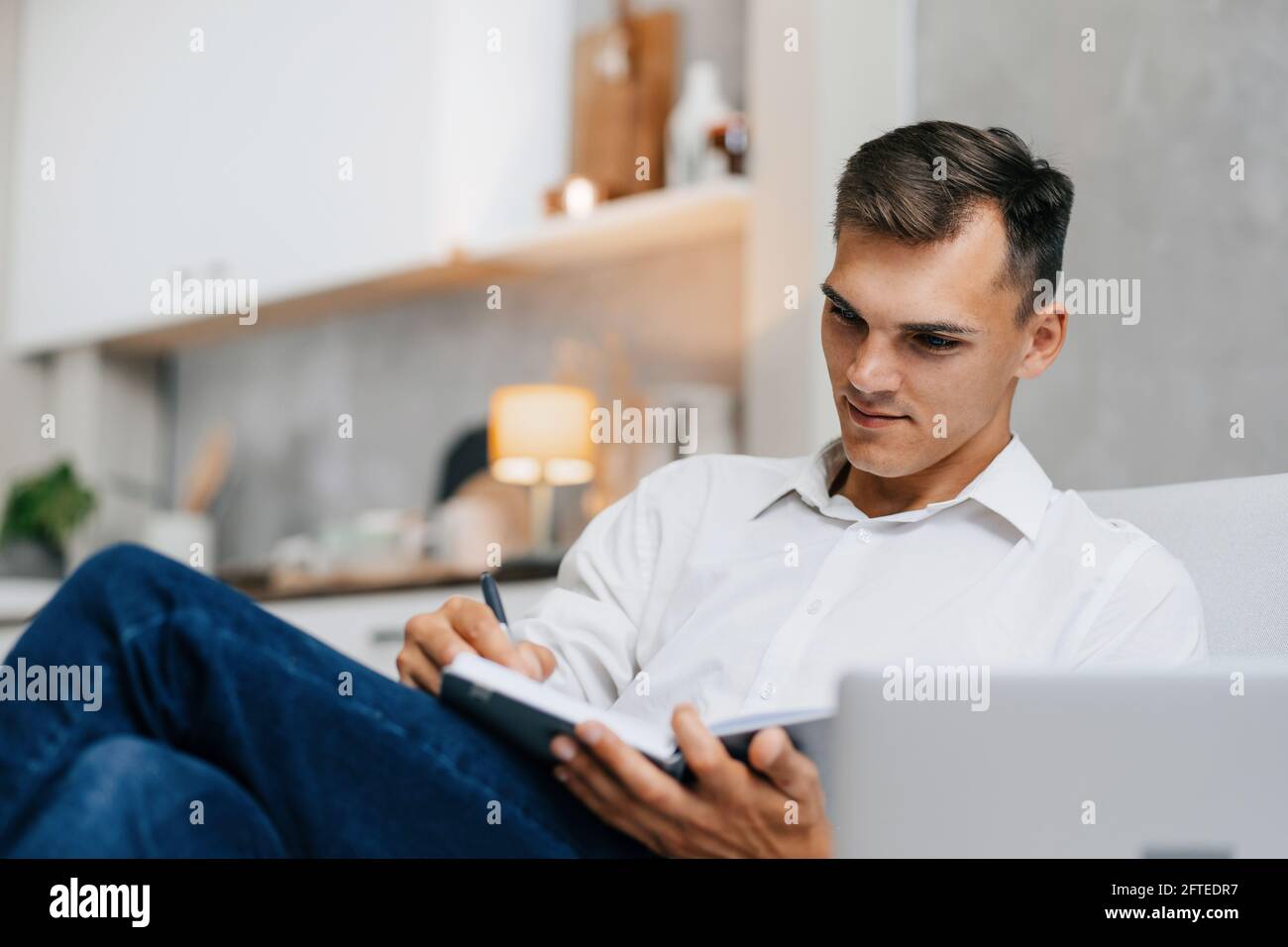 young man taking notes sitting on the couch . Stock Photo