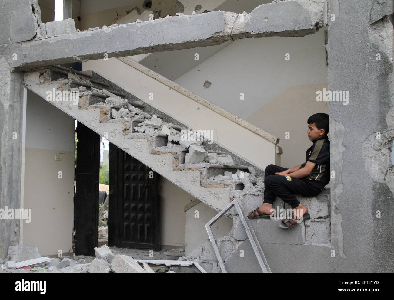 Gaza. 21st May, 2021. A Palestinian child sits at his house destroyed ...
