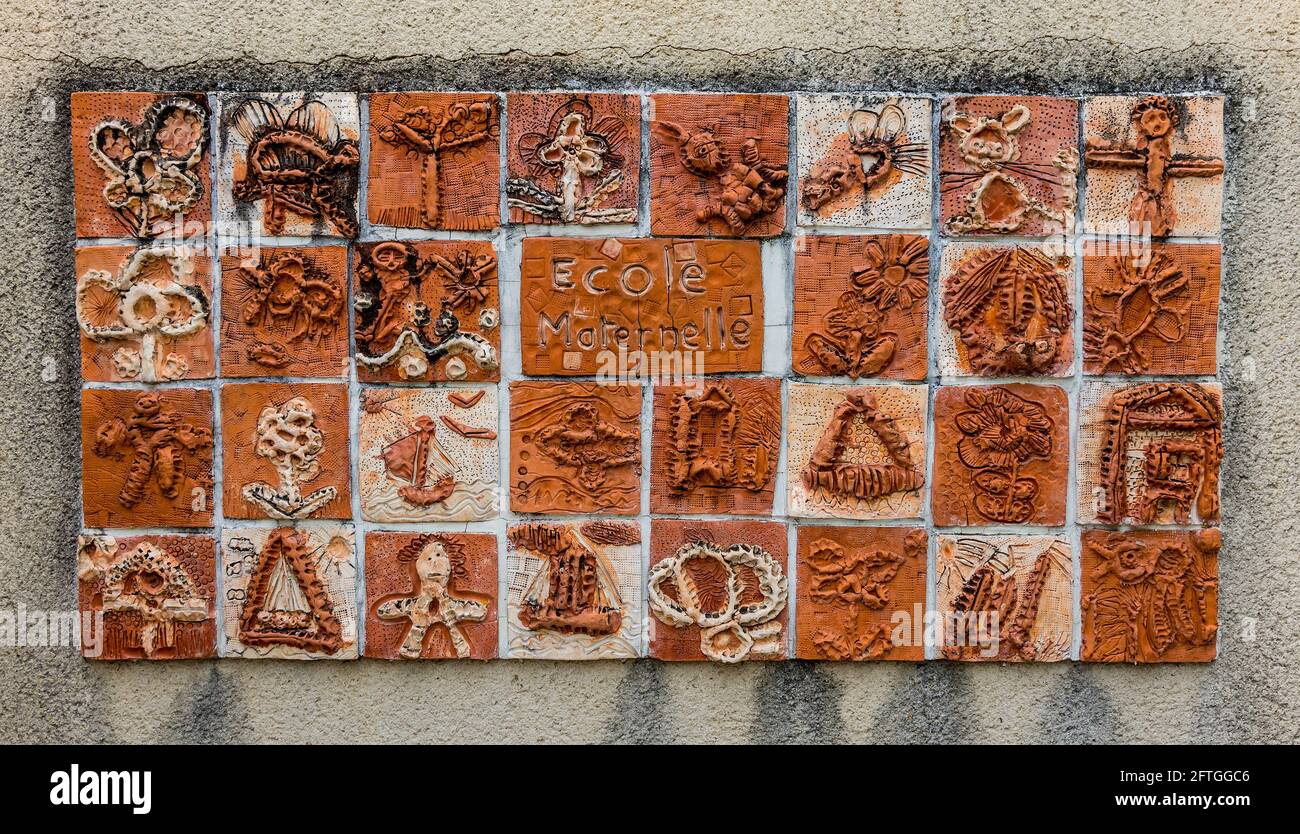 Decorative fired clay tiles made by children, mounted on school wall, Le Blanc, Indre (36), France. Stock Photo