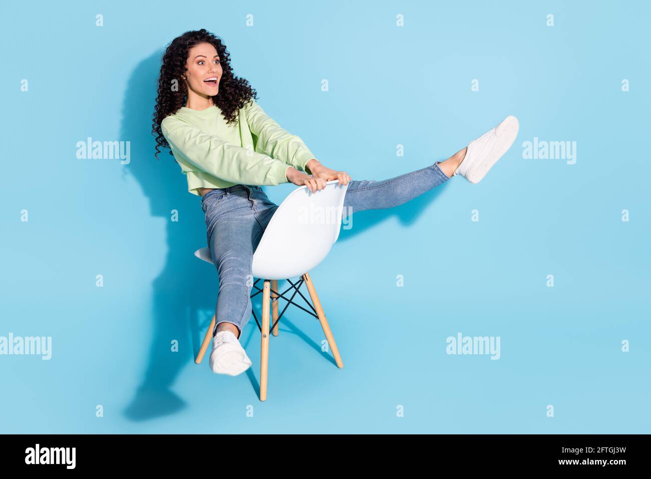 Photo of crazy funky lady sit chair ride look empty space wear pullover jeans isolated blue background Stock Photo