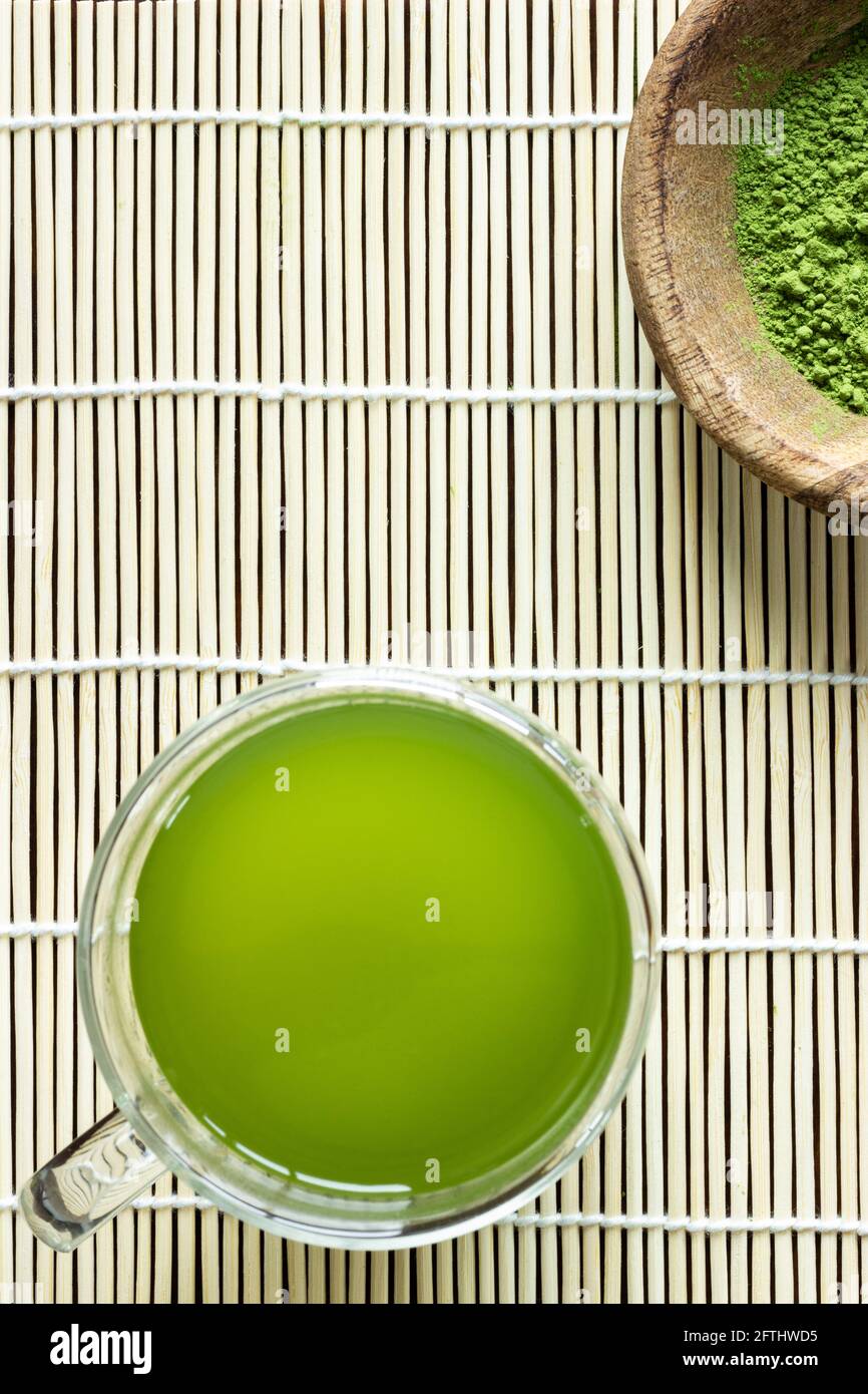 Matcha drink and powder on bamboo mat; Japanese green tea; serving; matcha on spoon; cup of green matcha tea Stock Photo