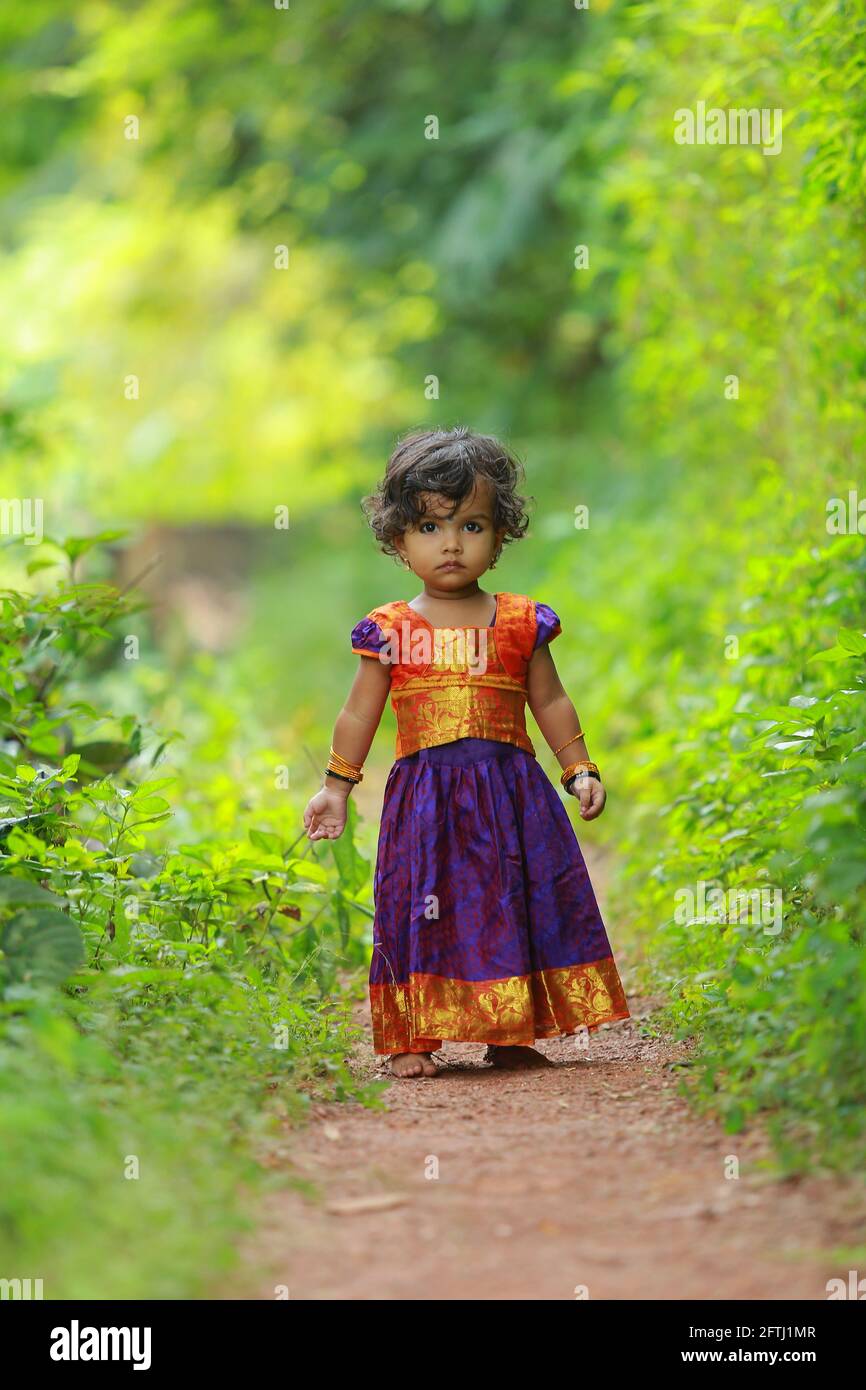 South Indian cute girl kid wearing beautiful traditional dress long skirt  and blouse,walking through village way with greenery background Stock Photo  - Alamy