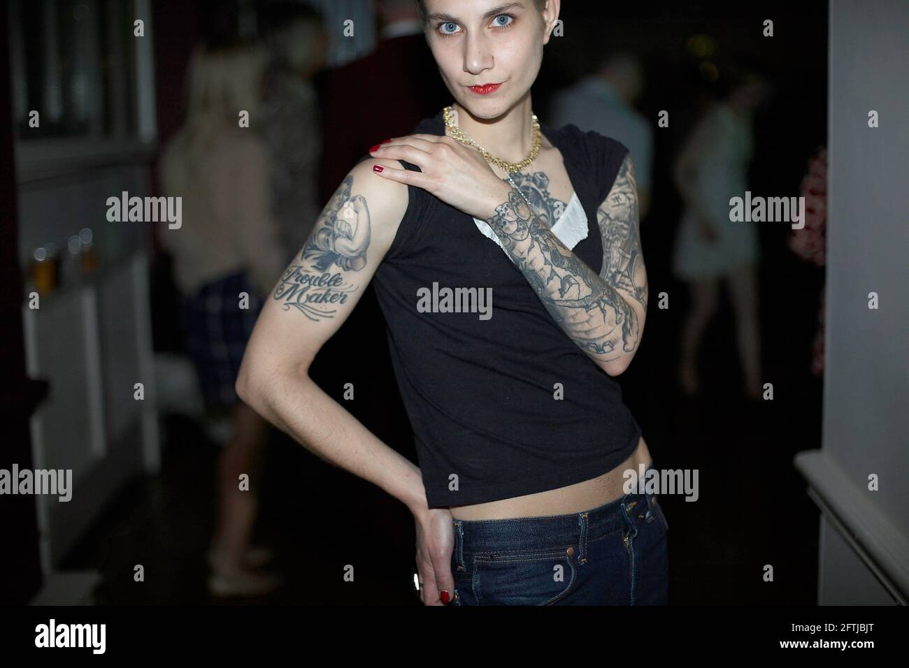 Tattooed woman with attitude showing her tattooed arm in night club , London ,UK Stock Photo