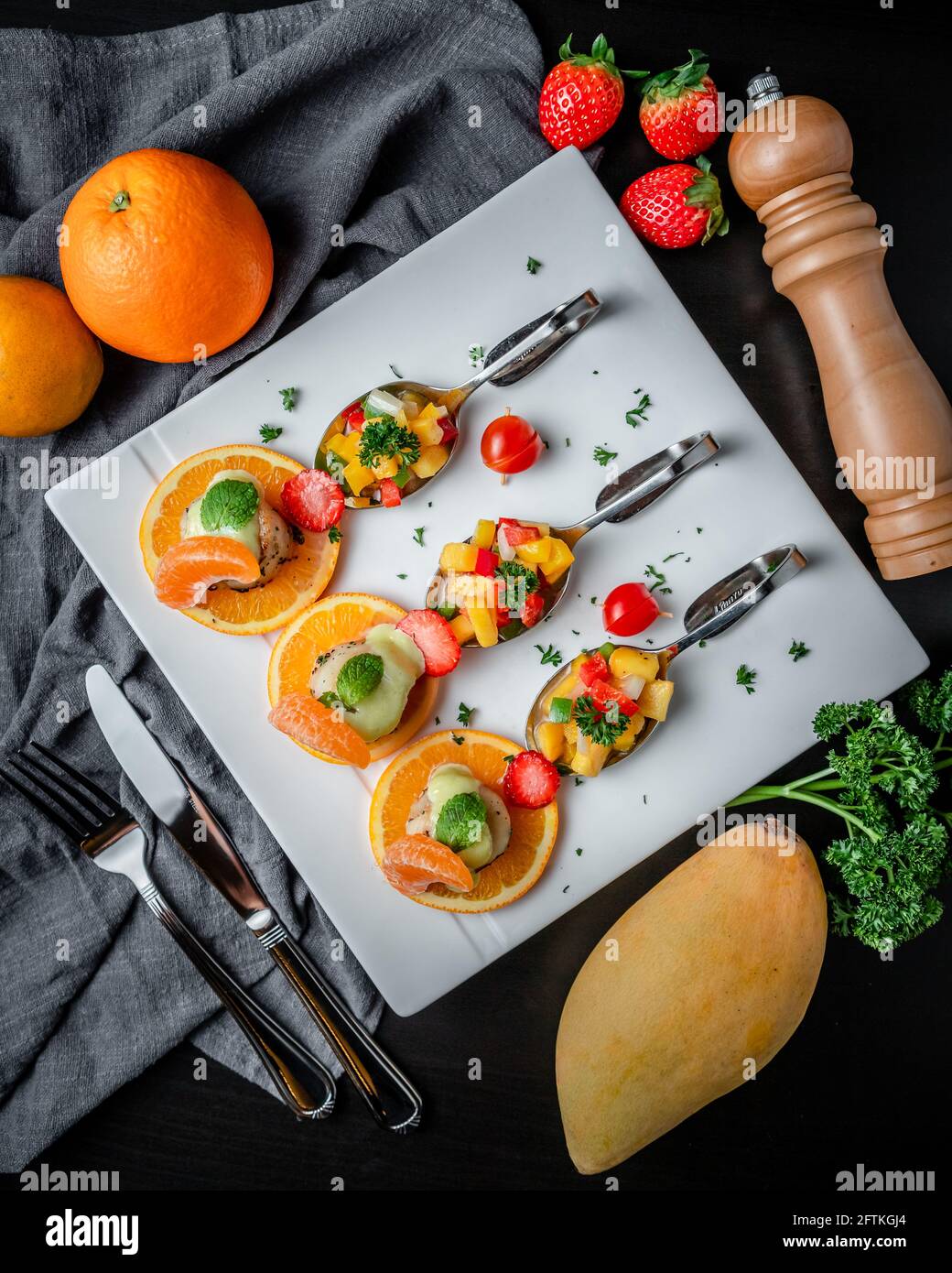 A Dish of Pan-Seared Scallops and Creamy Cheese Sauce Served with Sliced Orange and Fruit Salad on Happy Spoons. Stock Photo