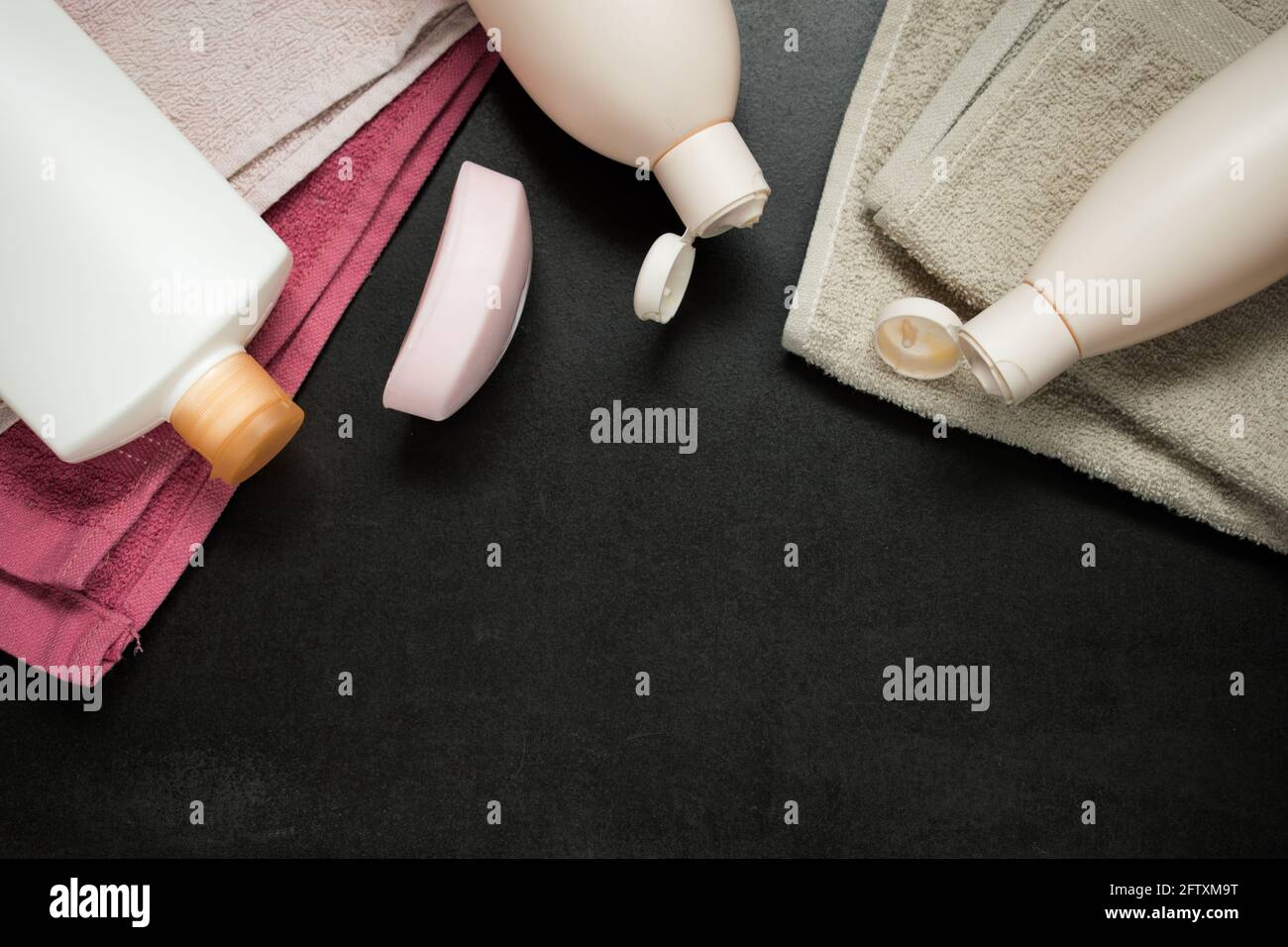 Some pink towels and some white bottles on a black wooden table in a spa Stock Photo